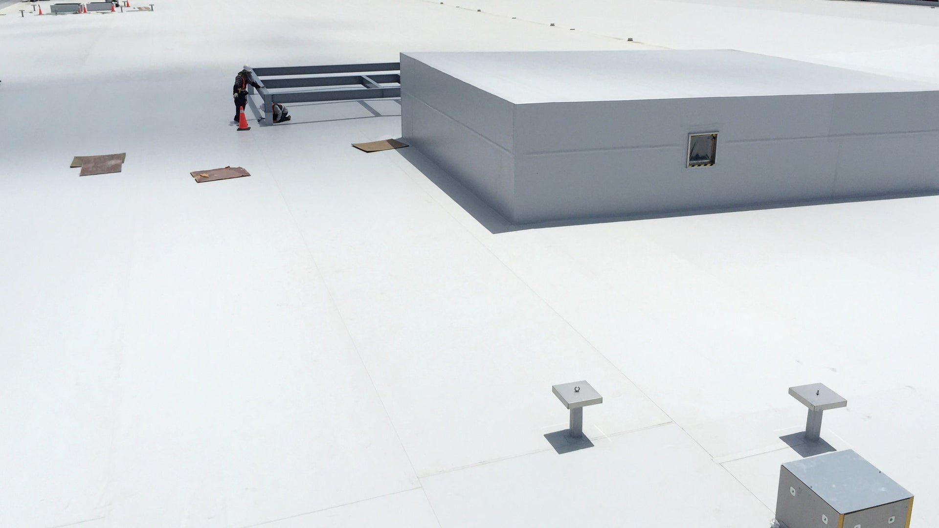 Workers on expansive white commercial rooftop