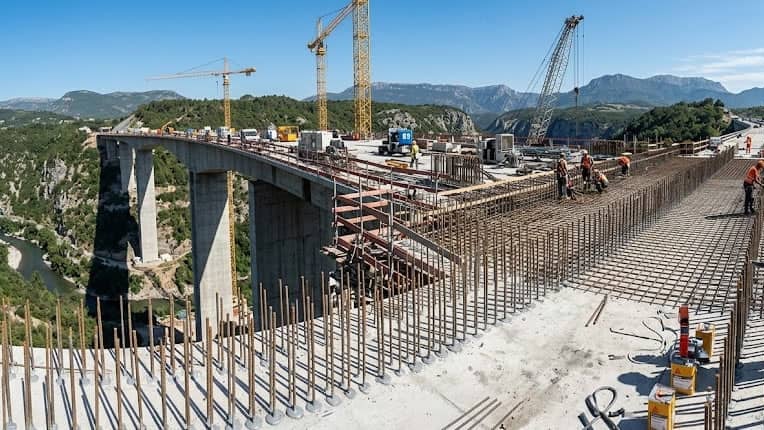 Construction workers building large mountain highway bridge