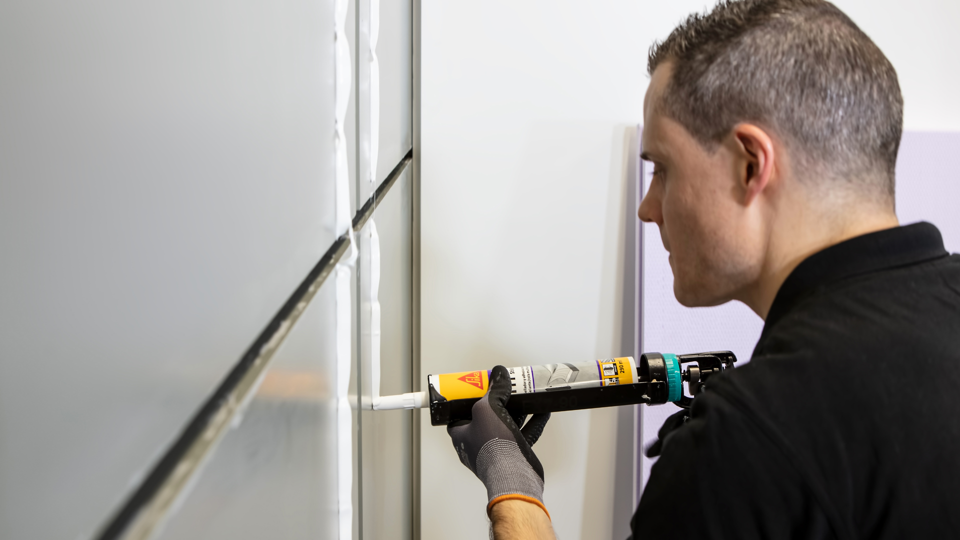man applying adhesive to wall