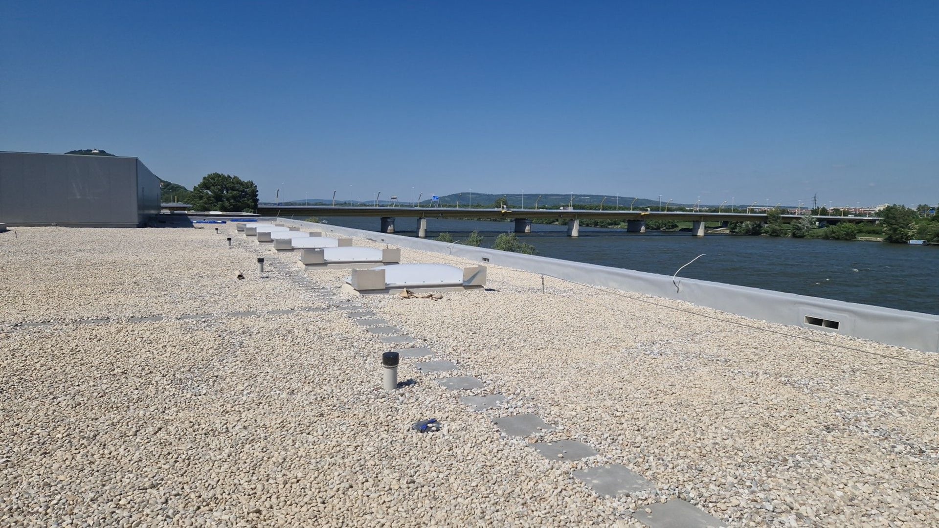 Bekieseltes Flachdach mit Blick auf eine Brücke und die Donau