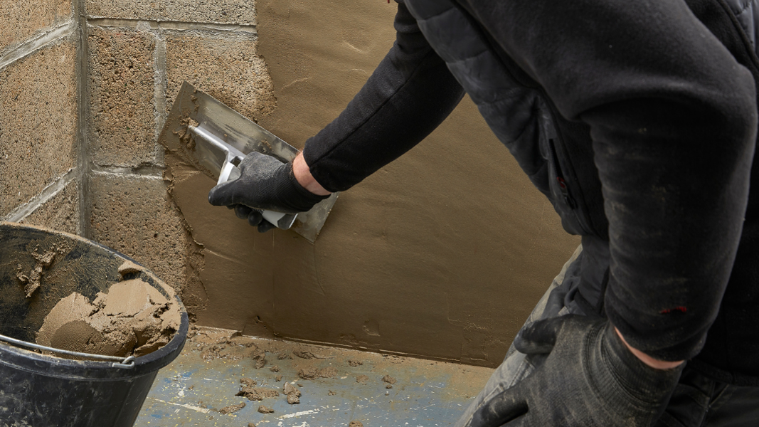 man applying waterproofing mortar to wall