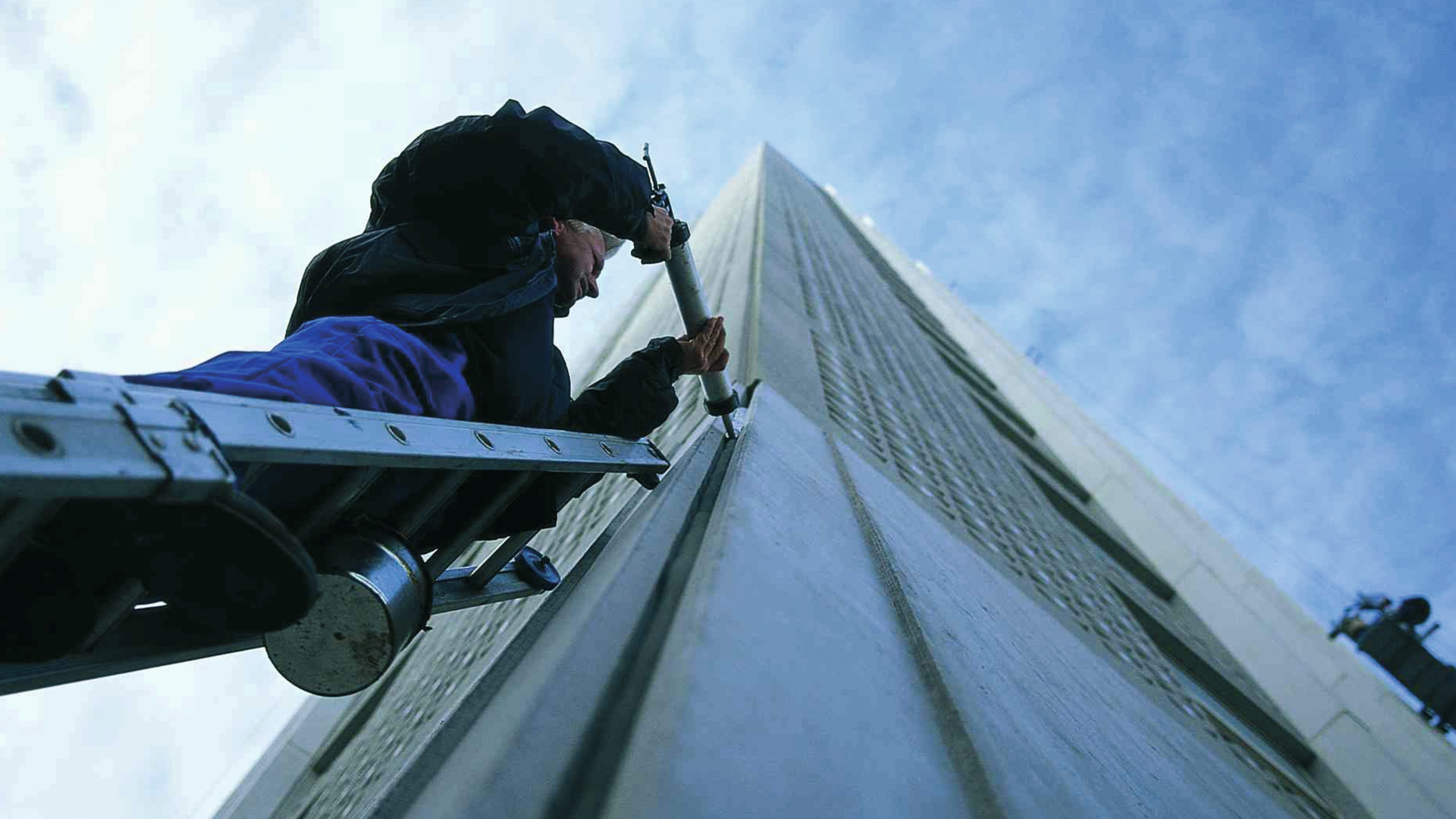 working on ladder sealing building facade