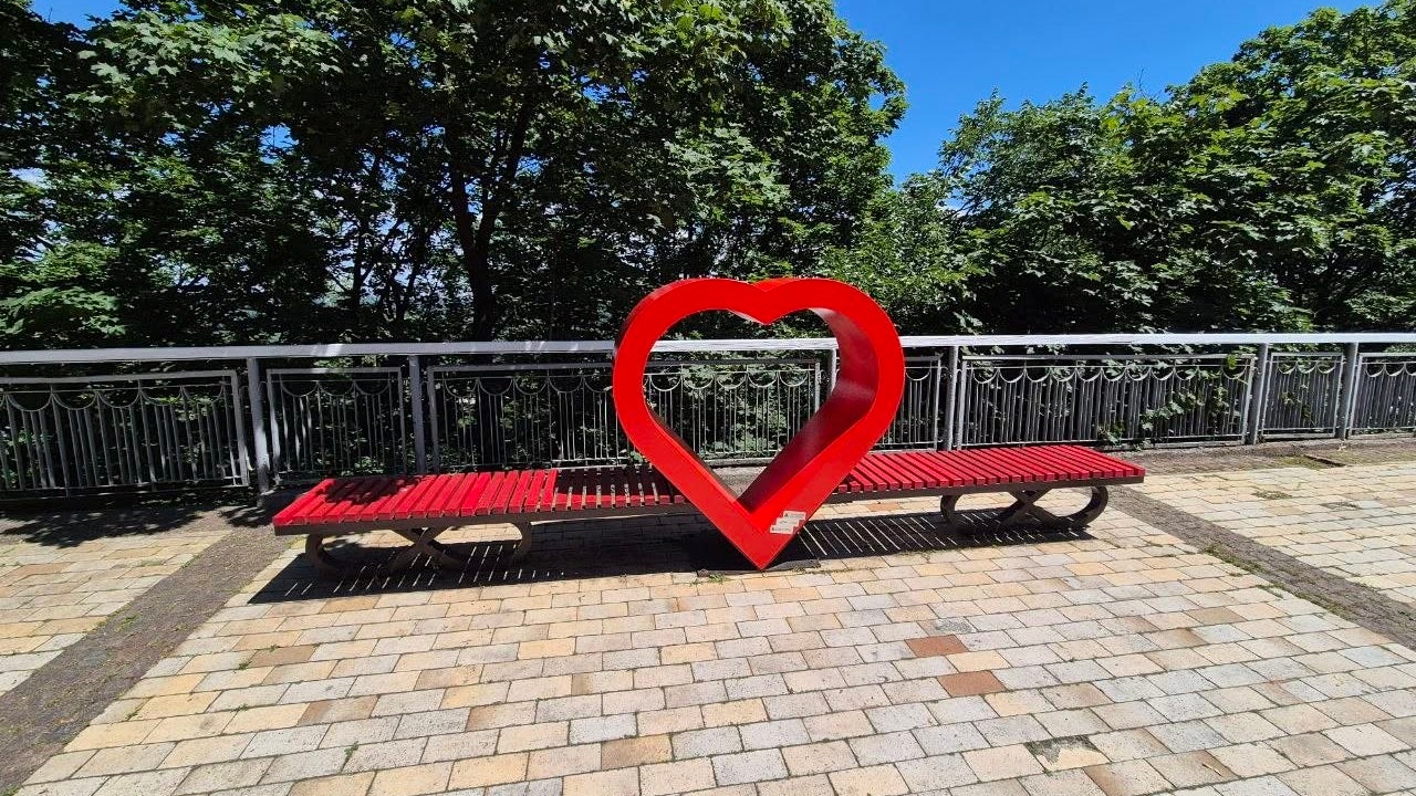 Red heart-shaped bench on sunny promenade