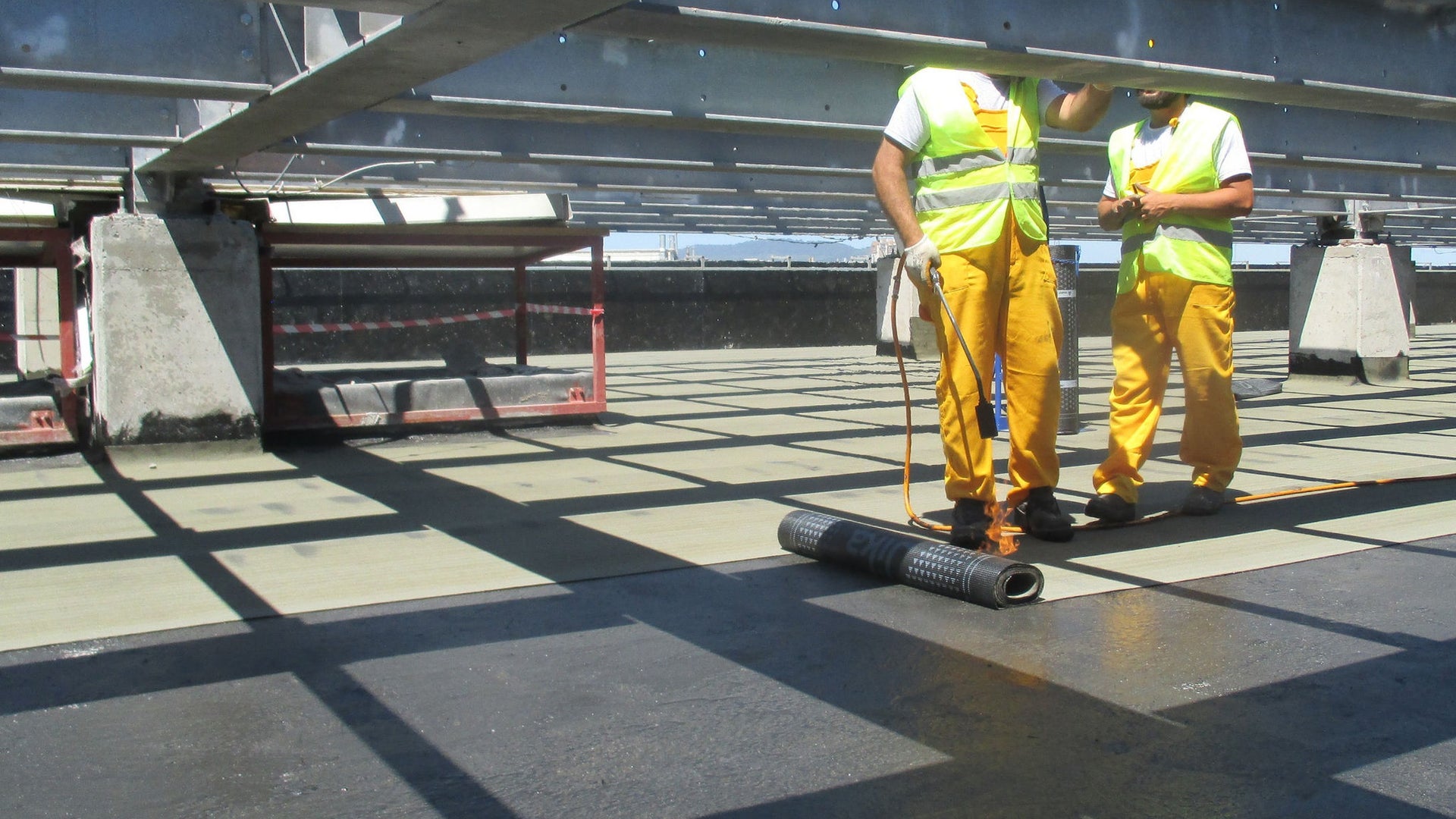 Construction workers applying waterproof membrane on roof