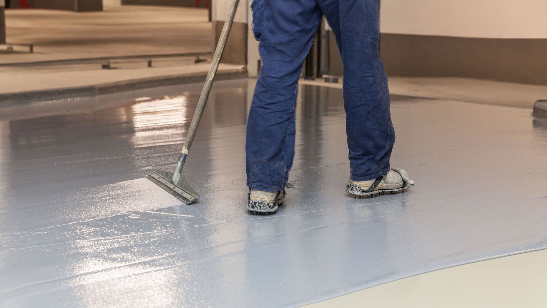 Worker applying smooth gray floor coating