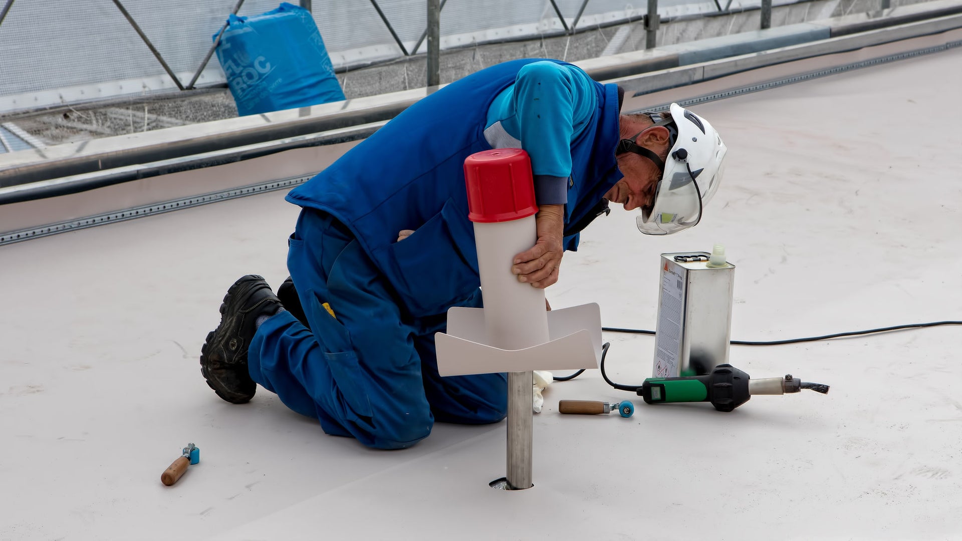 Construction worker installing rooftop ventilation component