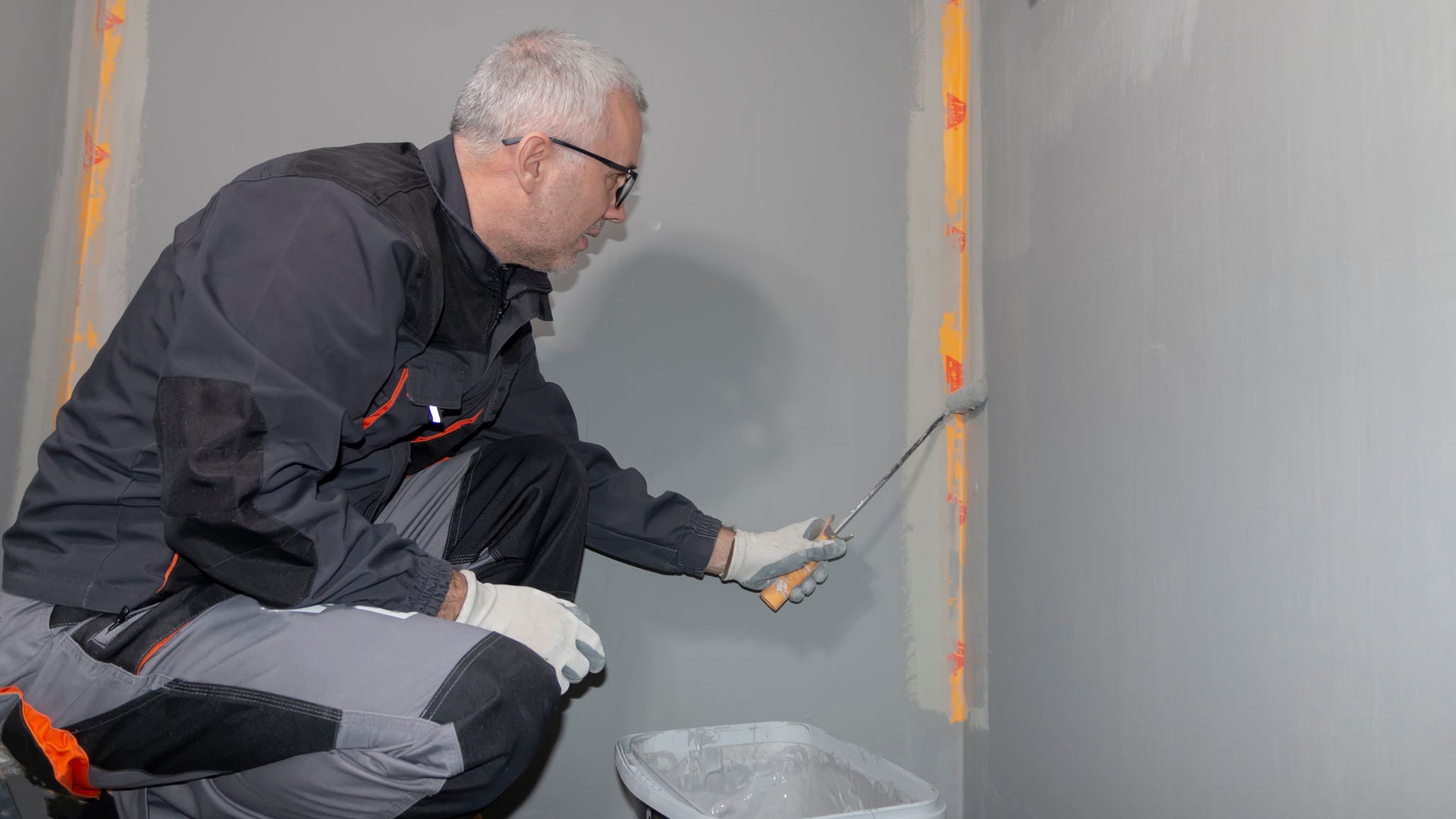 Worker applying sealant to interior wall