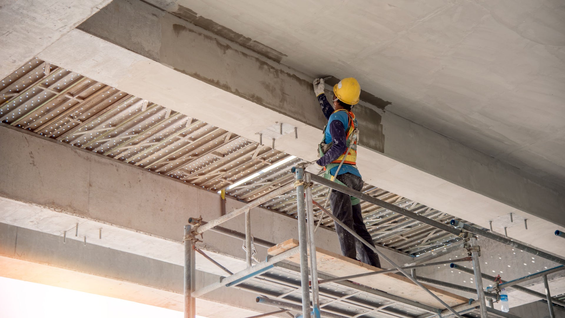 Construction worker applying concrete repair mortar to bridge beam