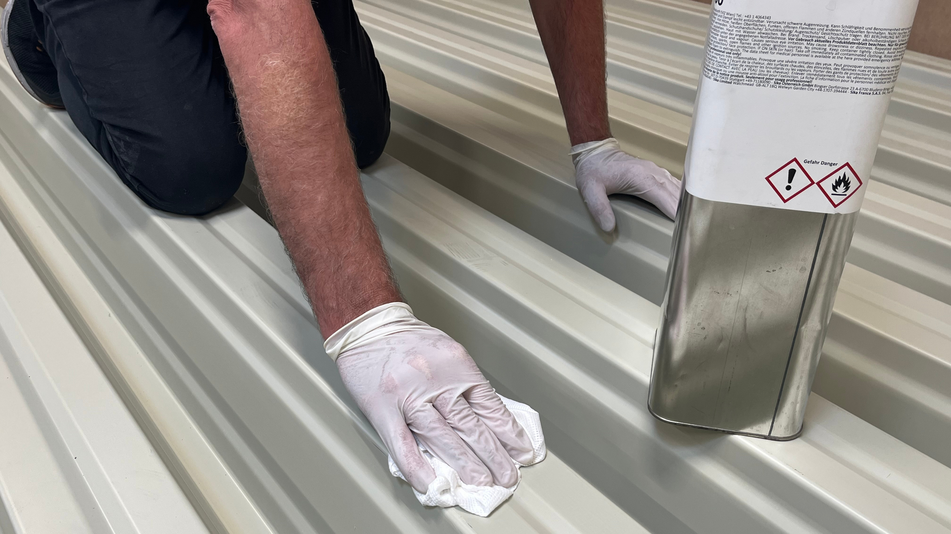 Worker Cleaning Metal Roof Panels with Solvent