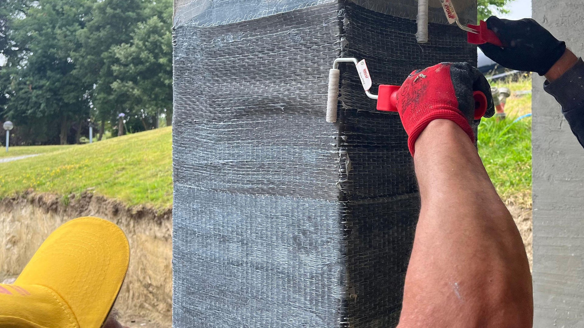 Workers applying coating to concrete column