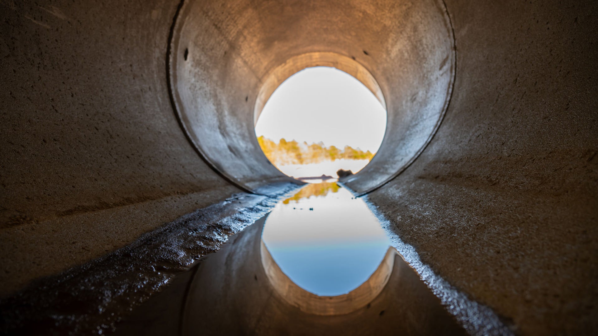 Inside a circular concrete drainage culvert with a trickle of water 