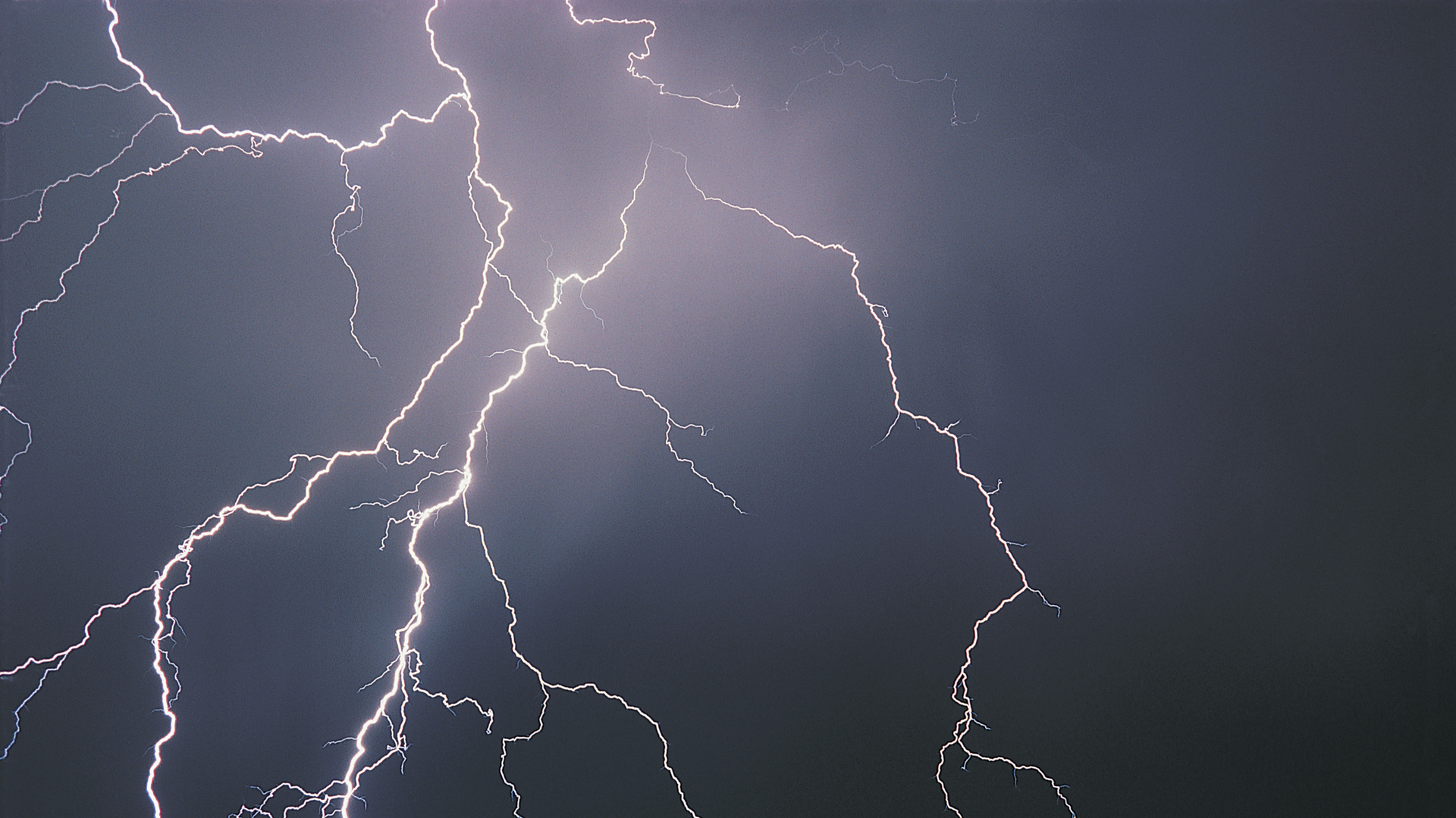 Multiple lightning bolts illuminate dark storm sky