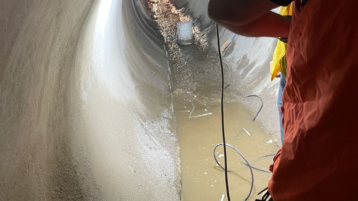 Worker inspecting large underground drainage tunnel