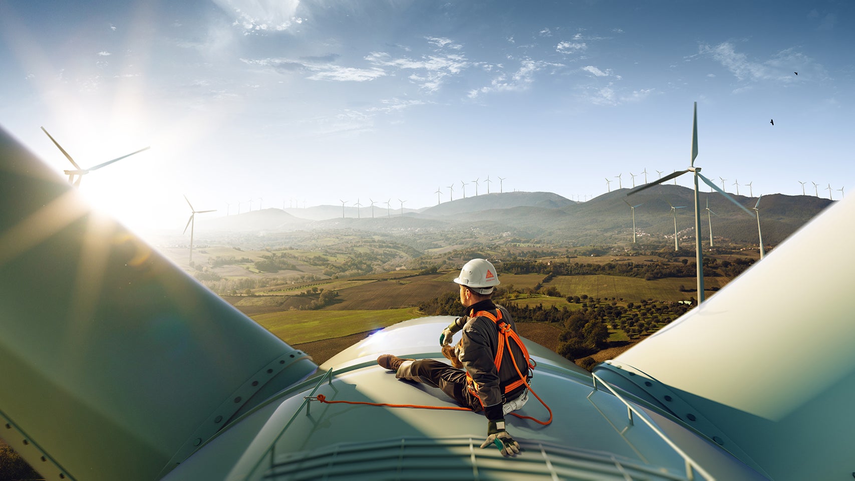 Engineer inspecting wind turbine at sunrise