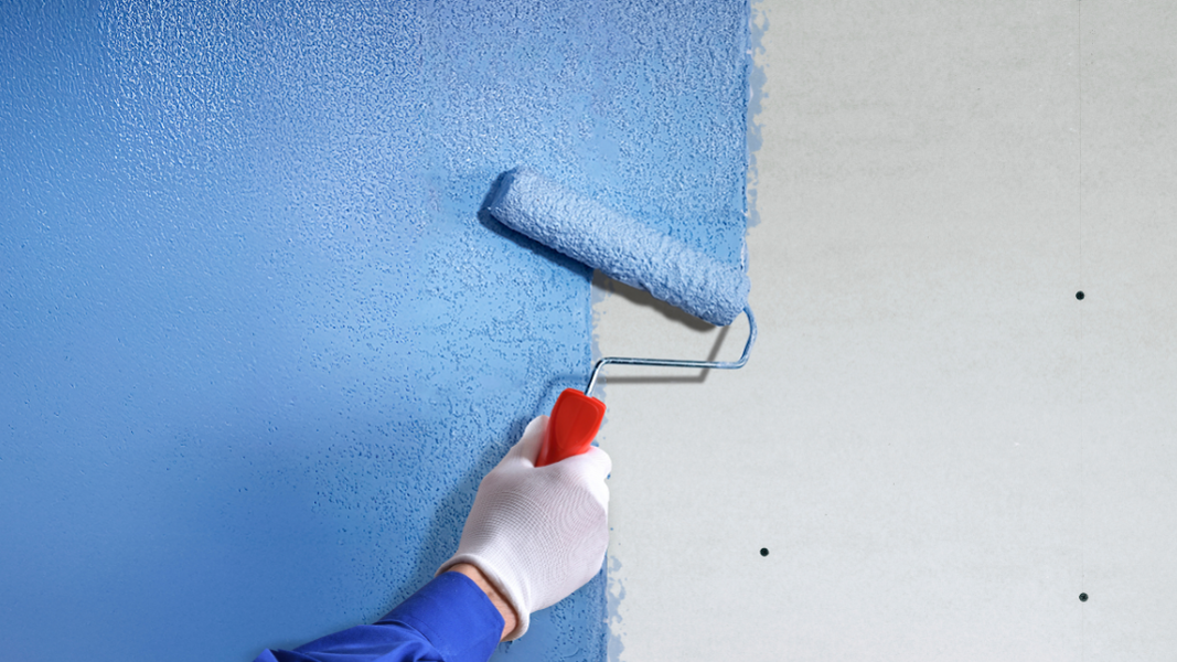 hand applying blue plaster bonding agent to wall