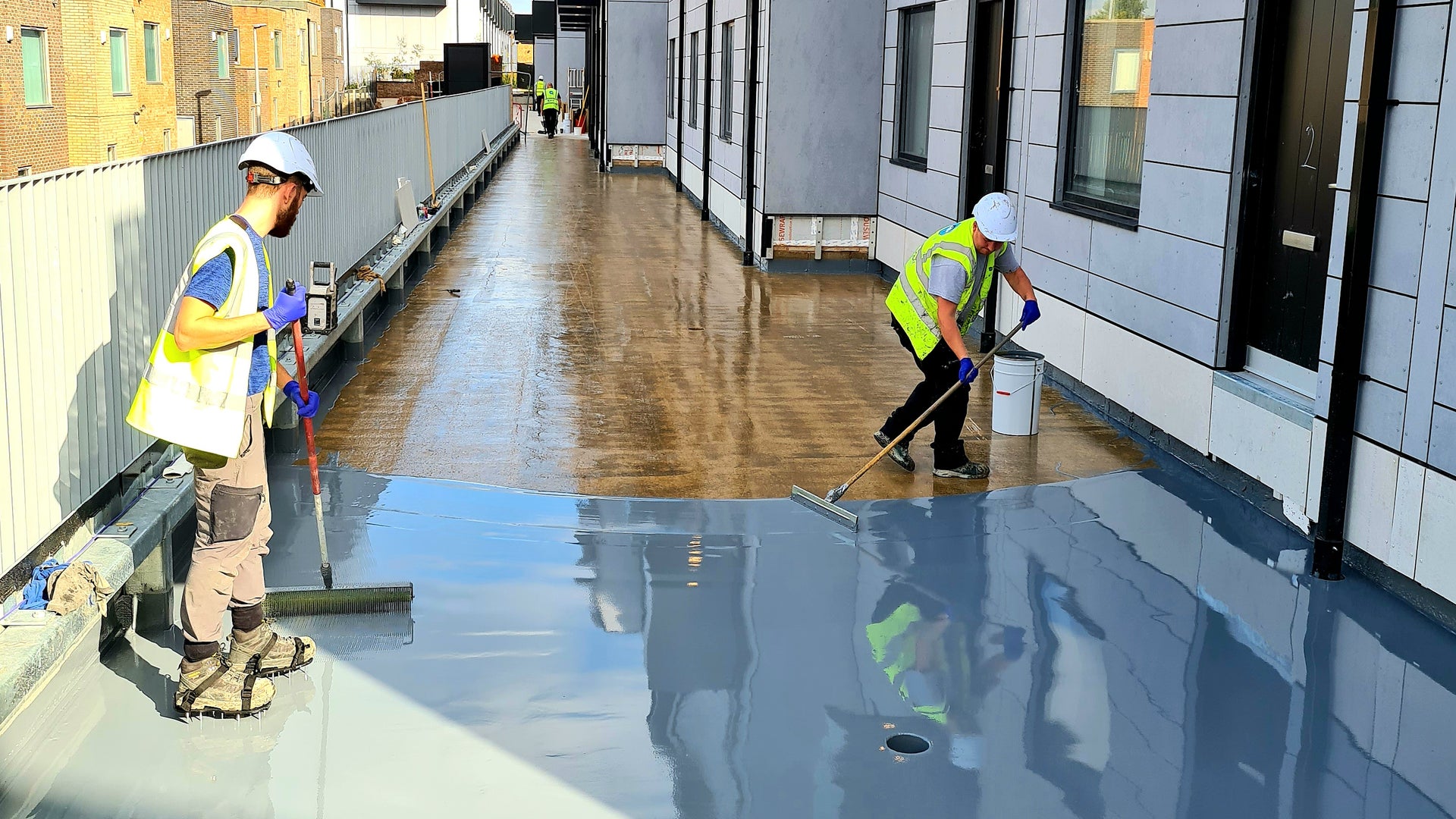 Workers applying Sikalastic liquid applied membrane to balcony of building