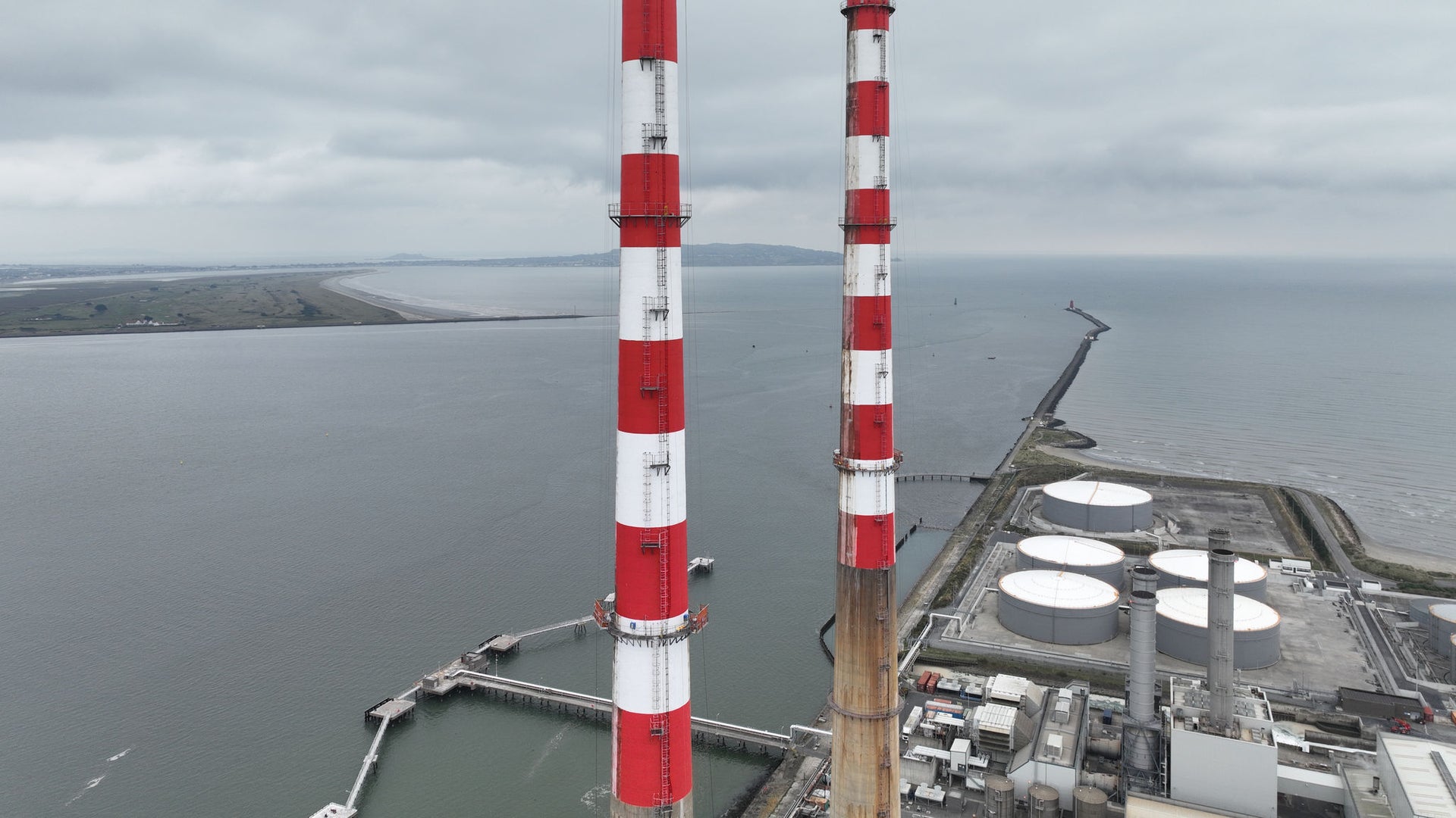 Red and white chimneys near industrial site