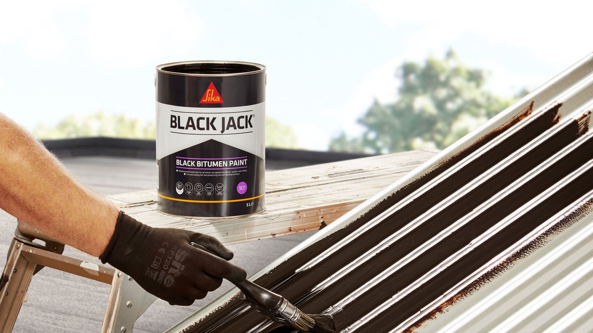Person painting Black Jack 901 Bitumen Paint onto corrugated metal roof panel