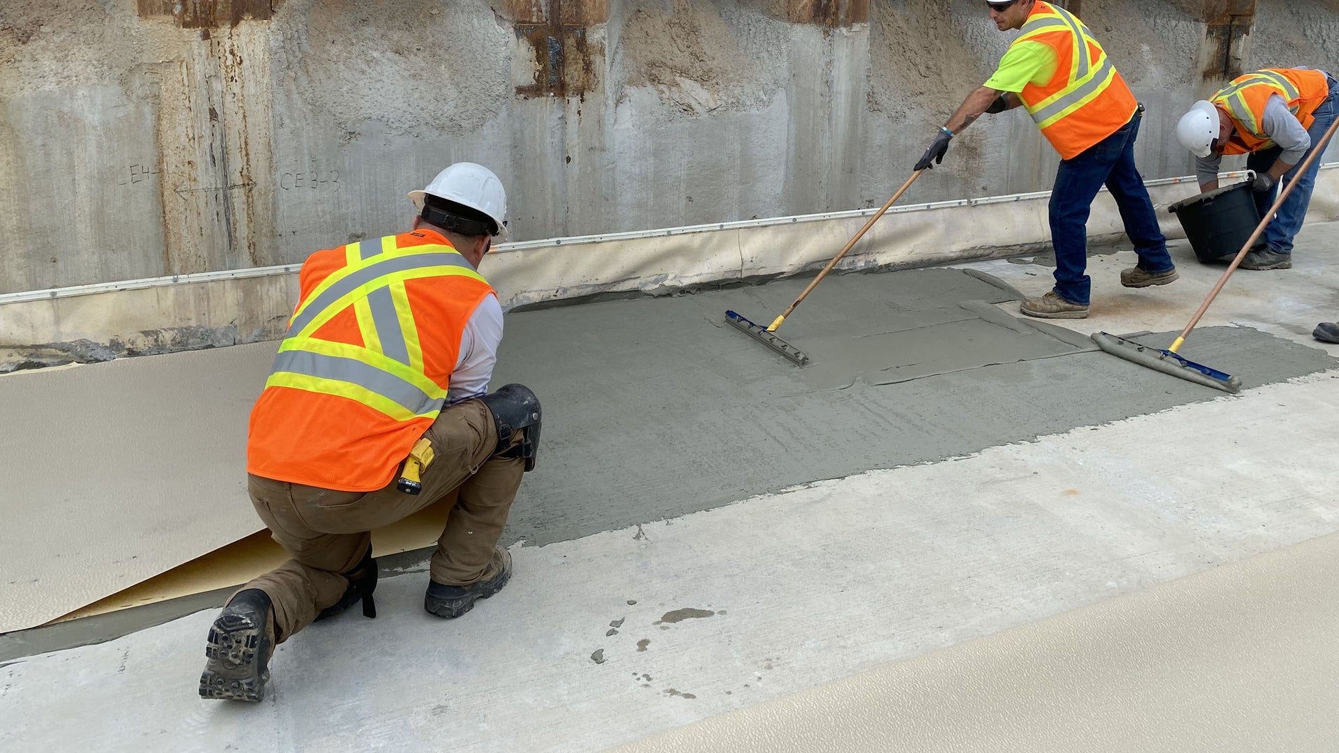 men applying watertight system to basement