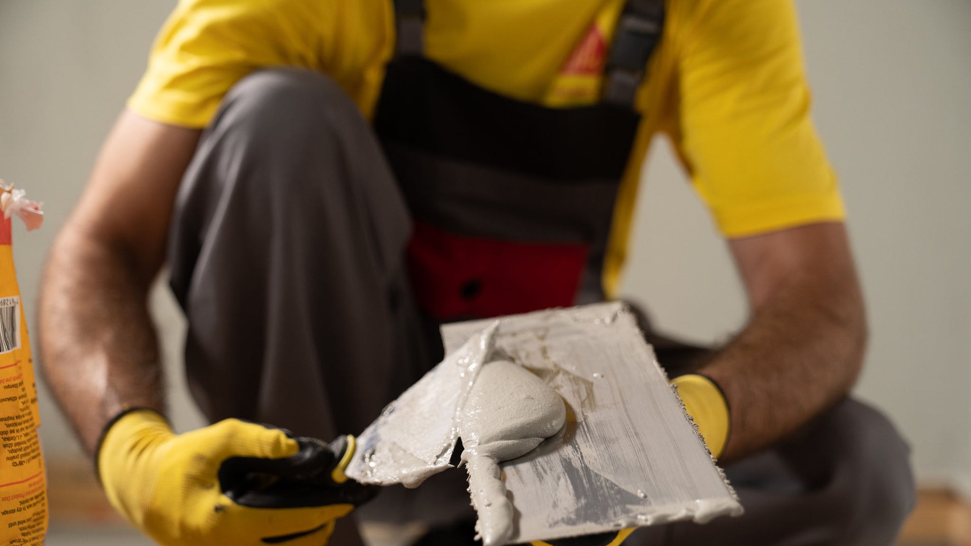 Man in yellow Sika tshirt applying Sika Igolflex-N waterproofing mortar with trowel