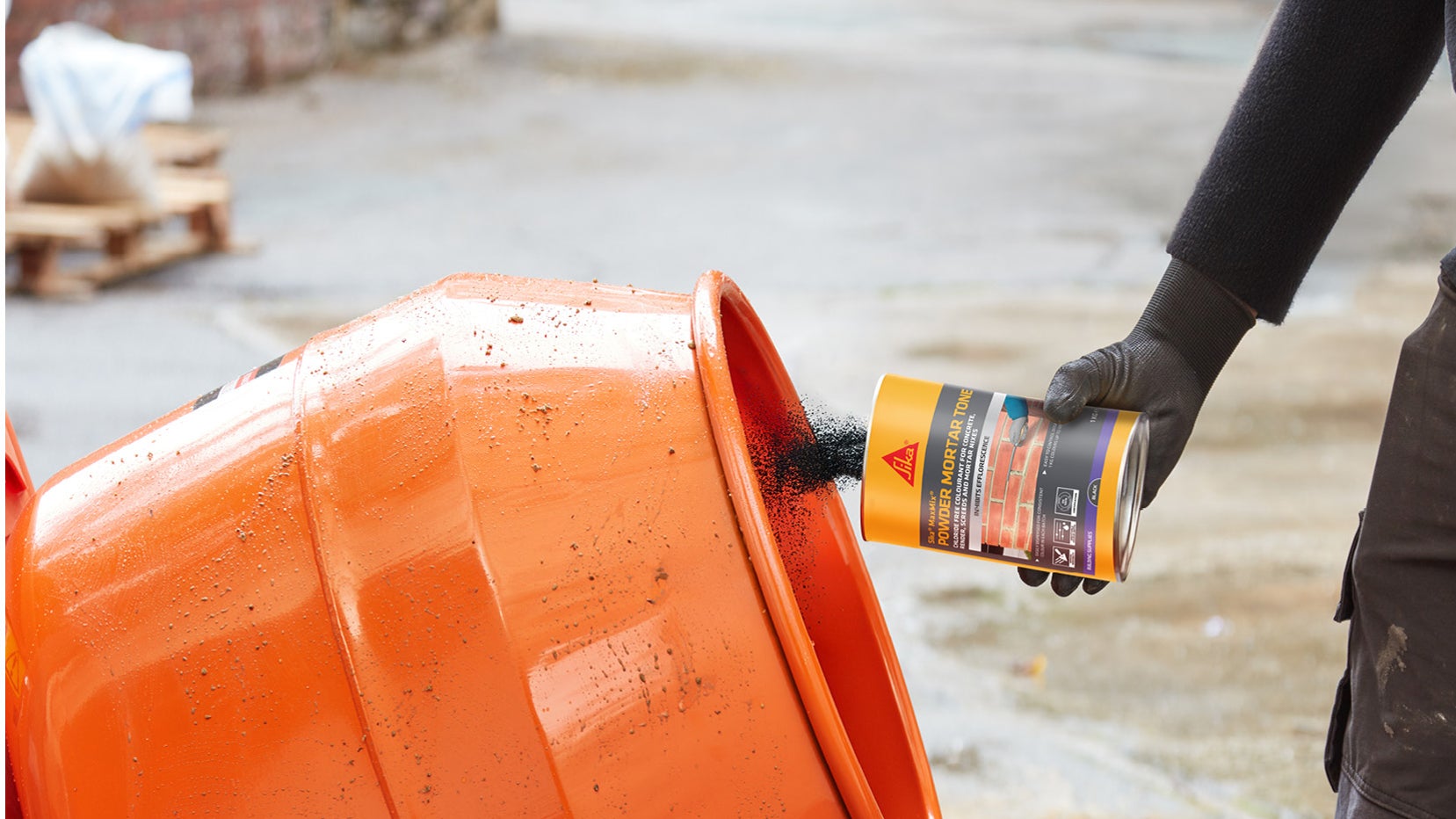 Worker adding powder to orange cement mixer