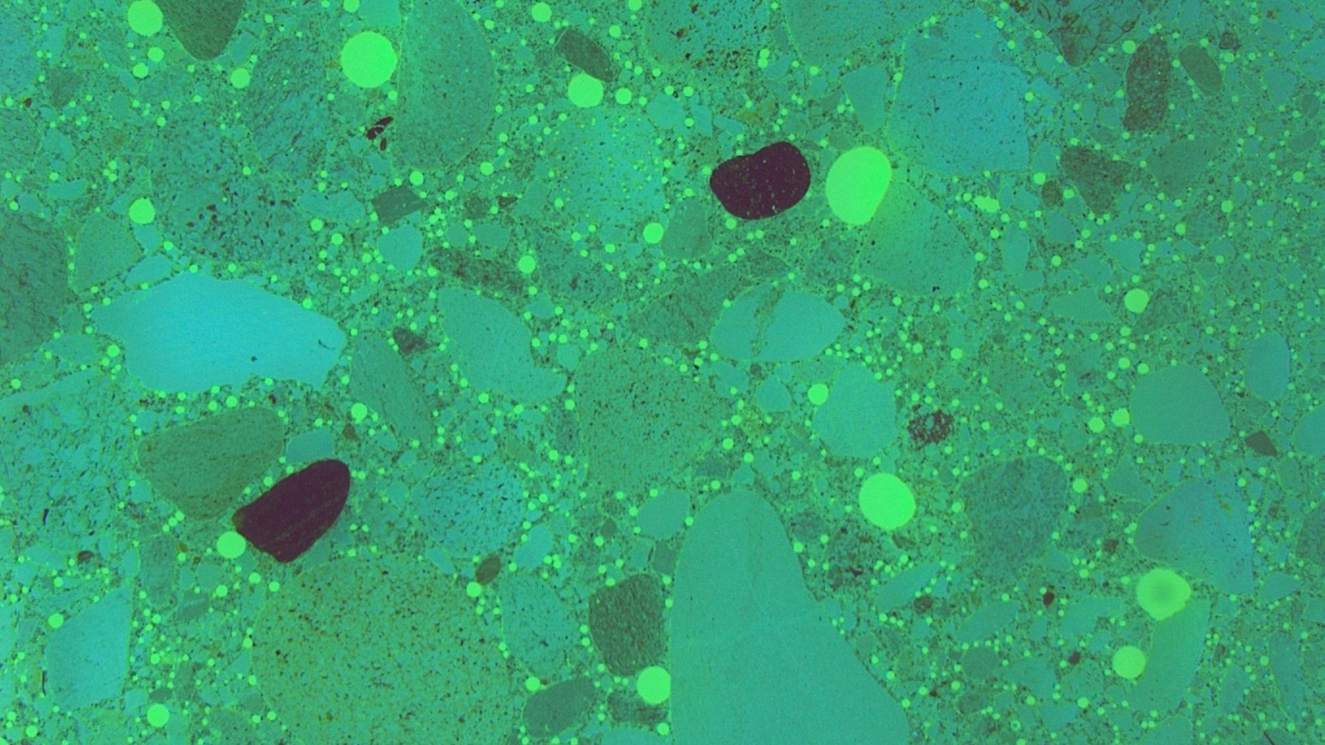 Thin slice of concrete under microscope in lab showing use of SikaControl AER air entrainer concrete admixture