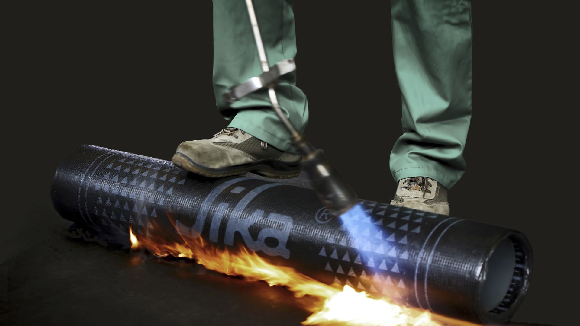 Foot rolling bitumen membrane and applying torch to adhere