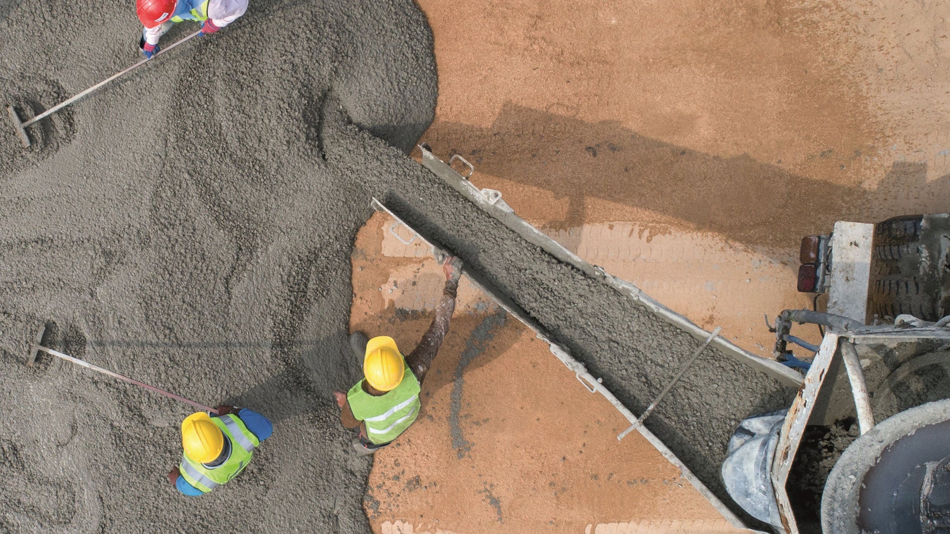 Construction workers spreading poured concrete from above