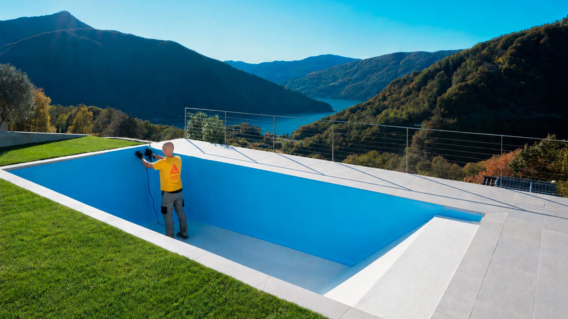 Workers inspect empty pool overlooking mountain lake