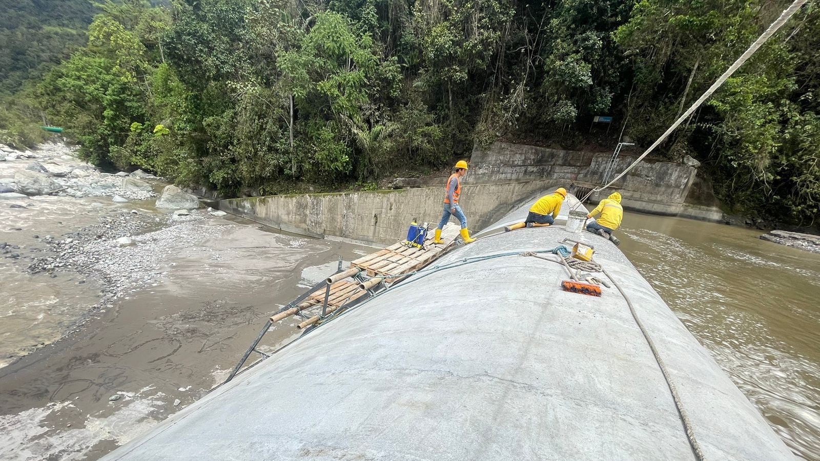 Workers inspecting dam structure over river spillway