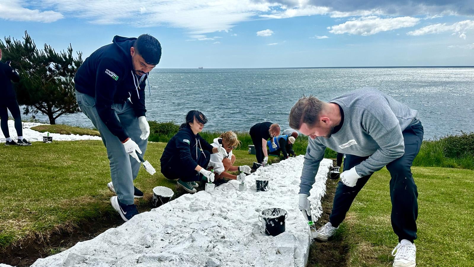 Volunteers painting large outdoor ground mural