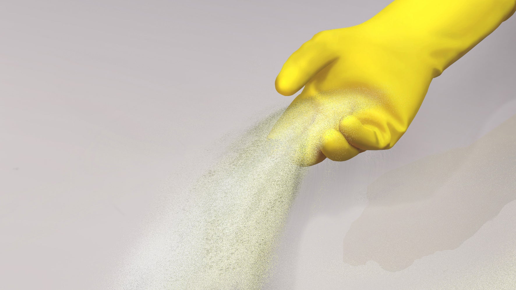 Hand with yellow glove scatters sand on the ground
