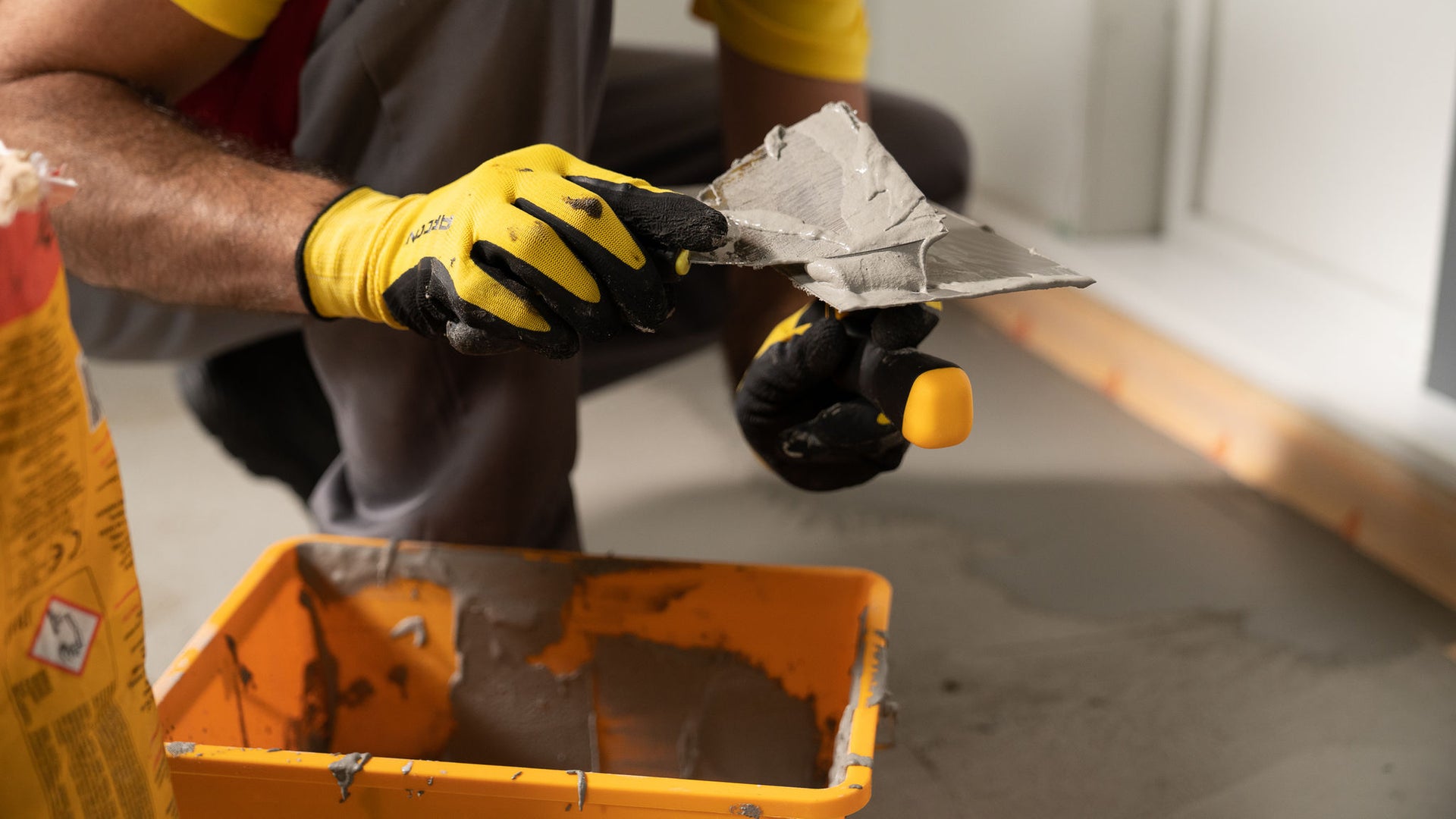 Man in yellow Sika tshirt applying Sika Igolflex-N waterproofing mortar with trowel