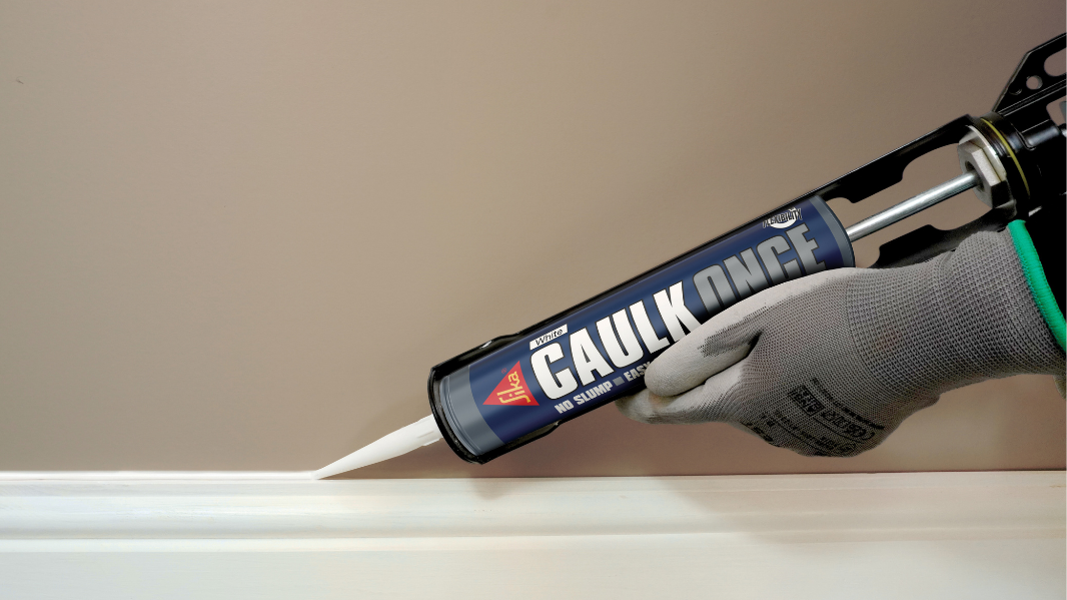 Hand applying caulk with caulking gun