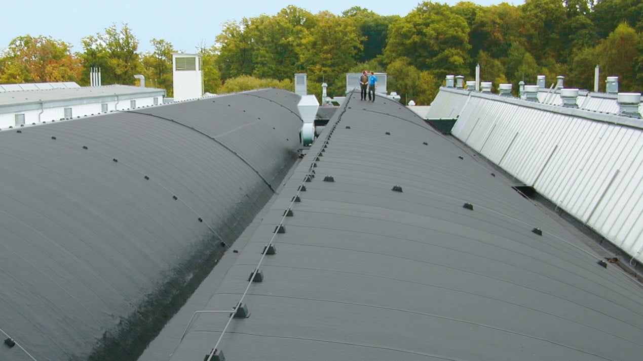 Workers inspect large commercial flat roof