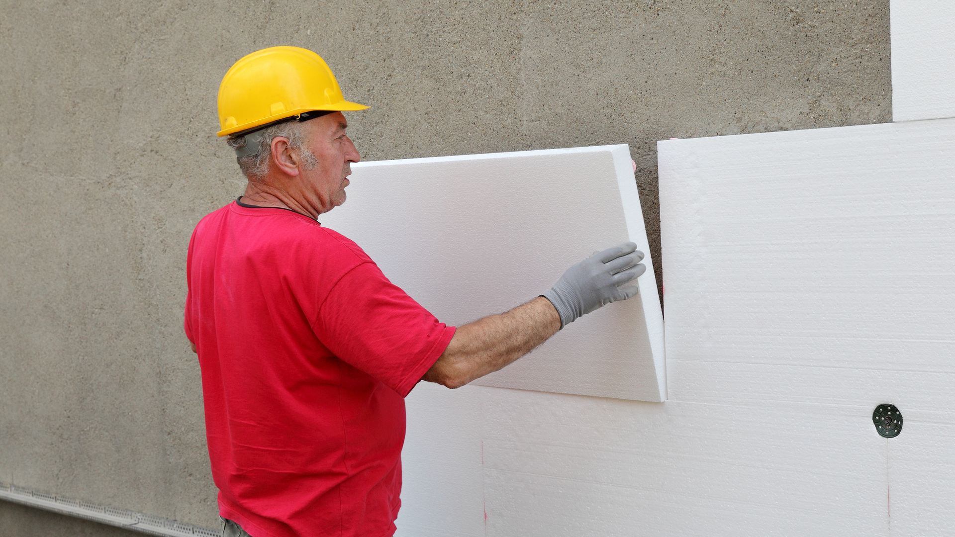 Worker installing insulation panels on wall