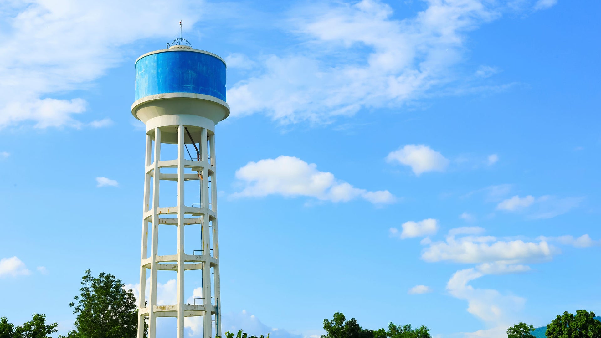 Tall blue water tower against bright sky