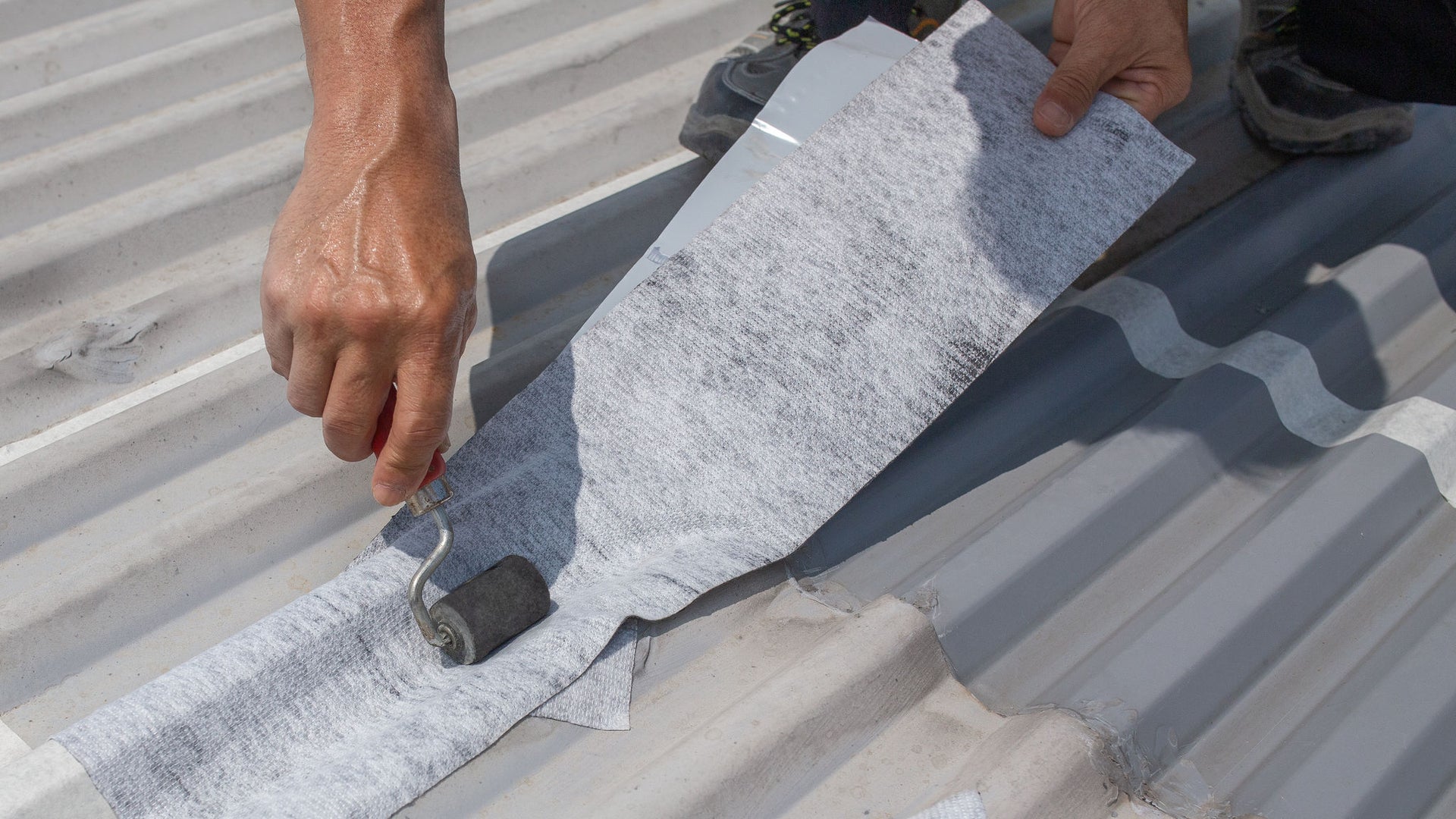 Worker applying repair tape on metal roof