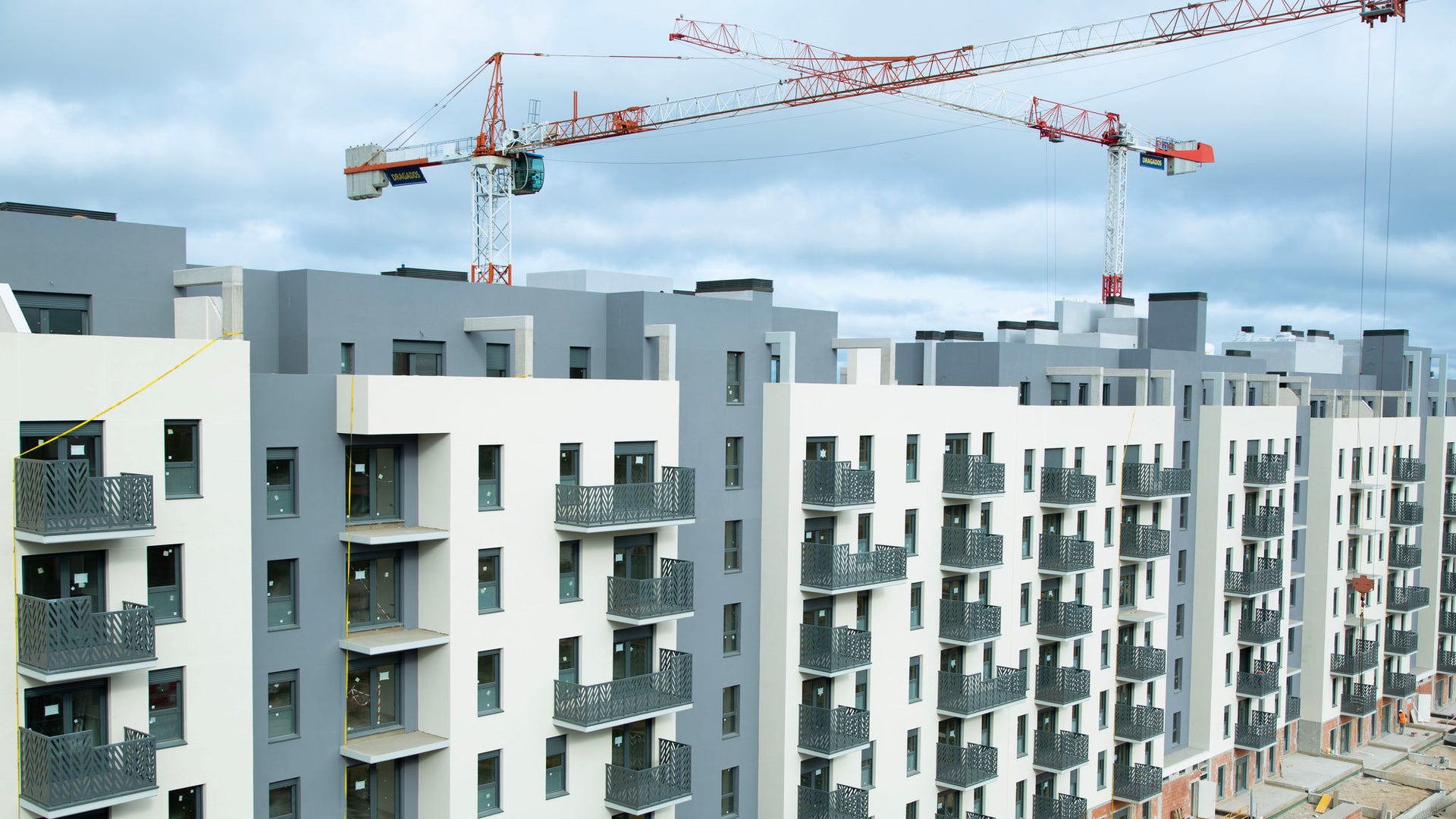 Modern apartment complex under construction with cranes