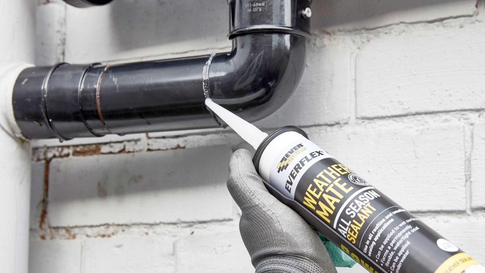 Black sealant being applied to drain pipe