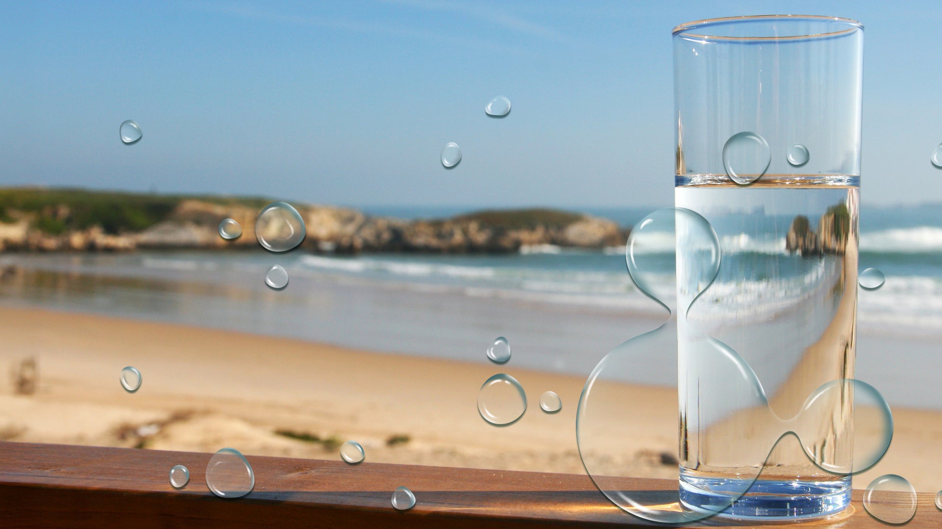 glass of water sitting by beach 