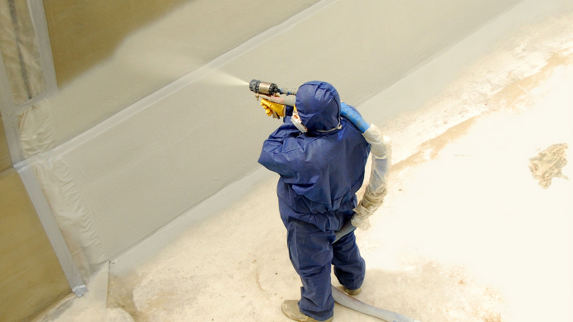 Worker spraying concrete wall with Sikagard material