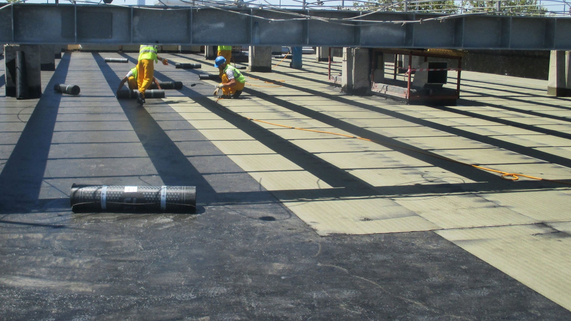 Construction workers installing commercial flat roof membrane
