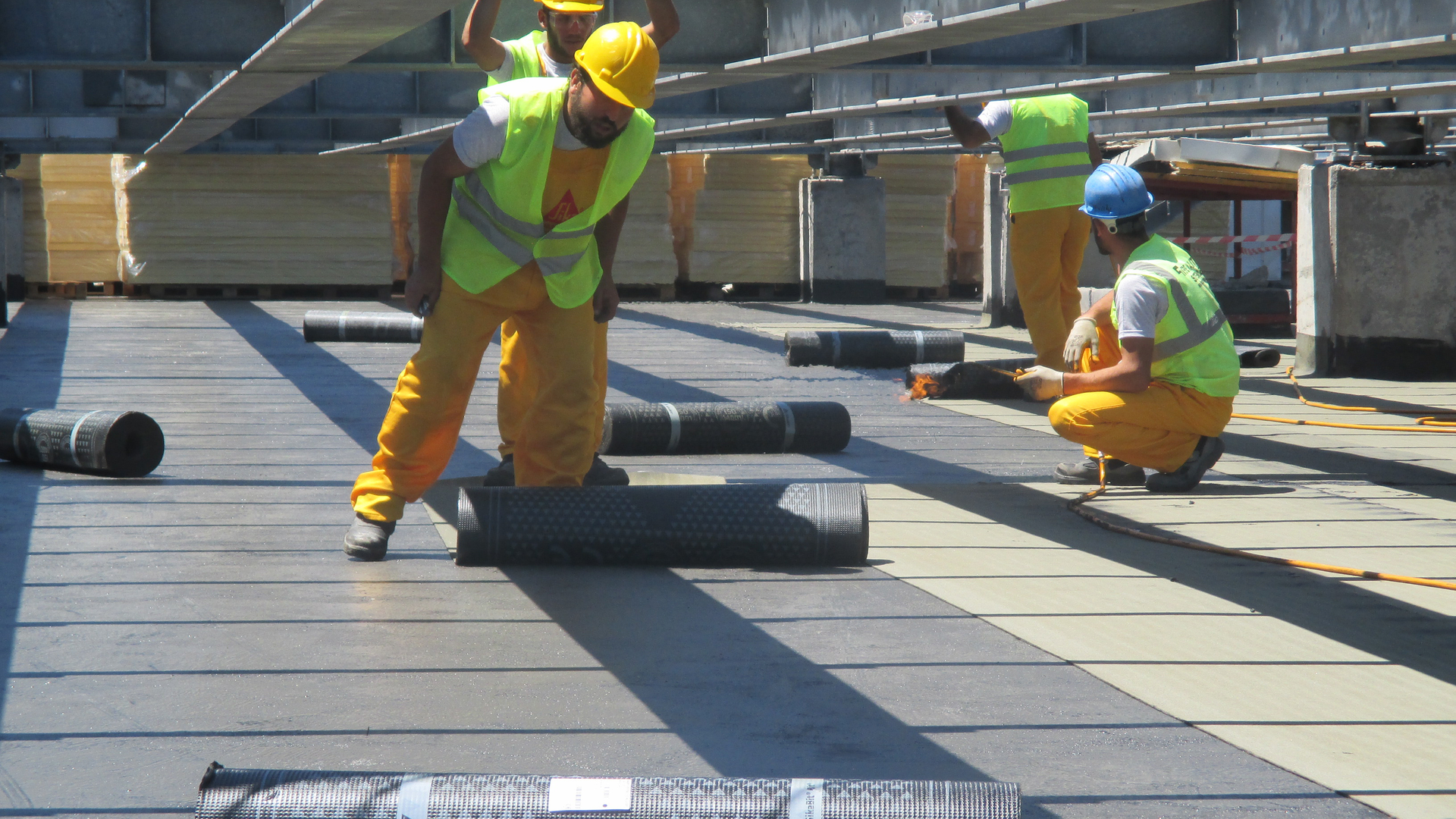 men applying bitumen roofing membrane