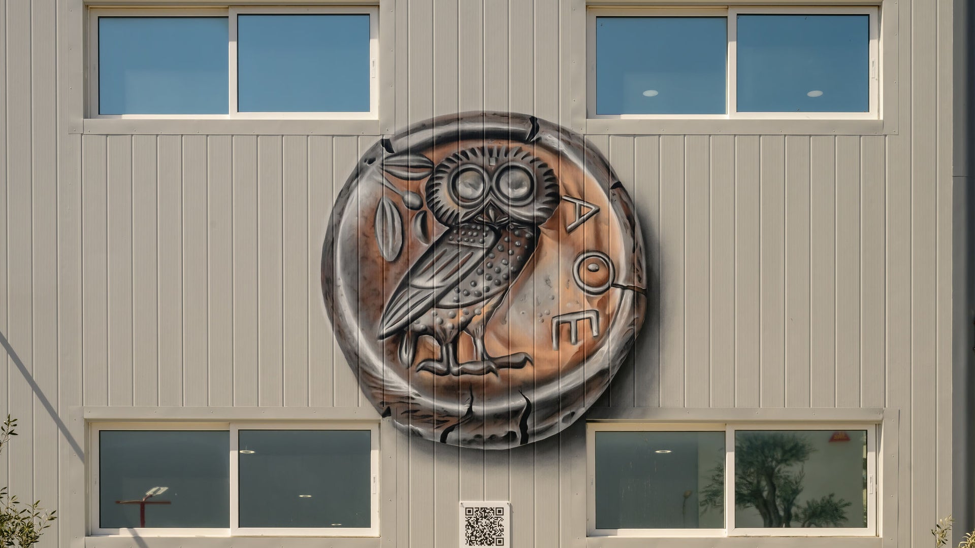Owl coin mural on modern building facade