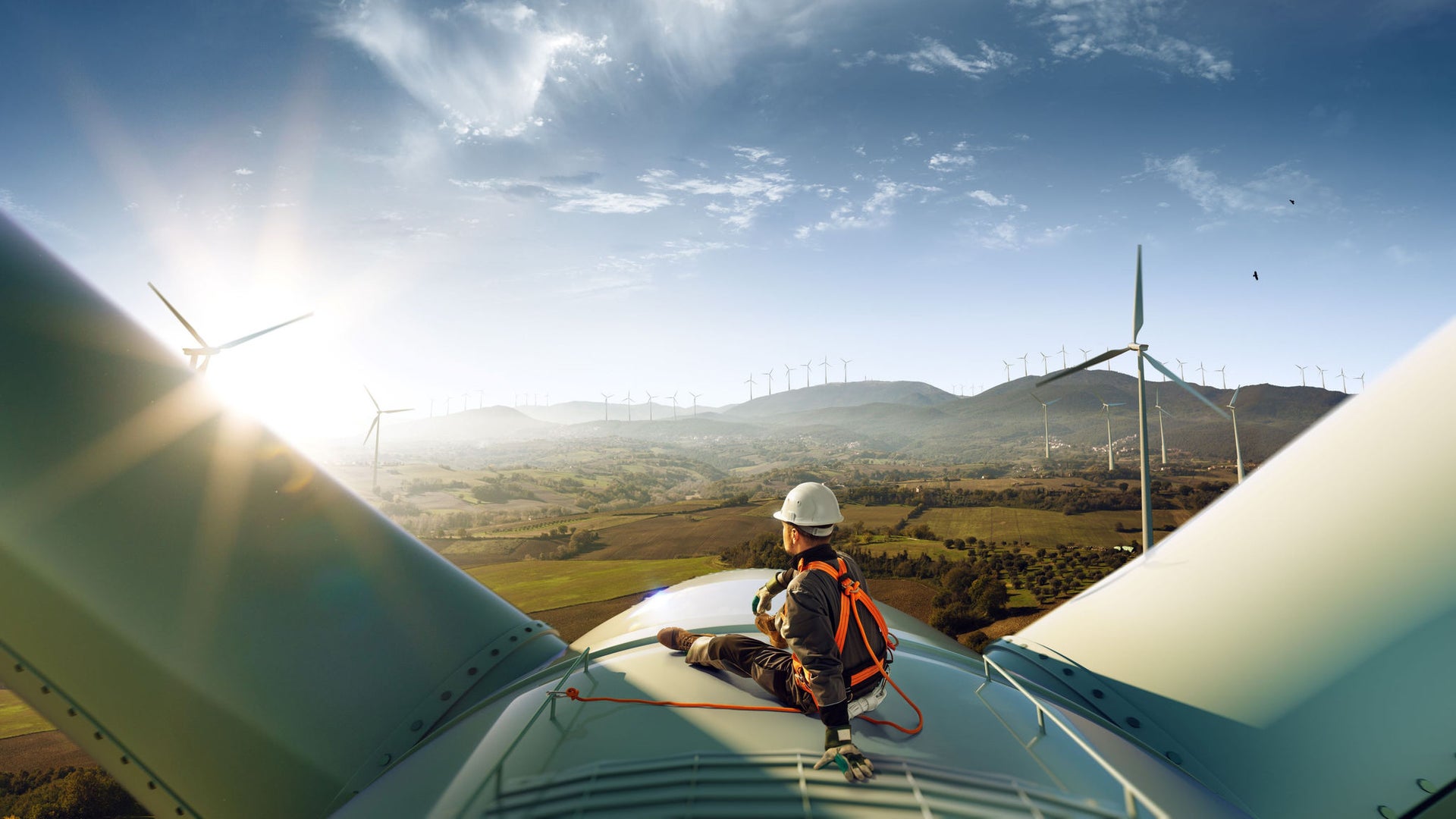 Worker sat on a wind turbine looking our to fields