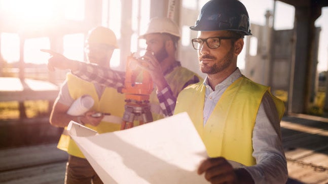 Construction workers reviewing site plans outdoors