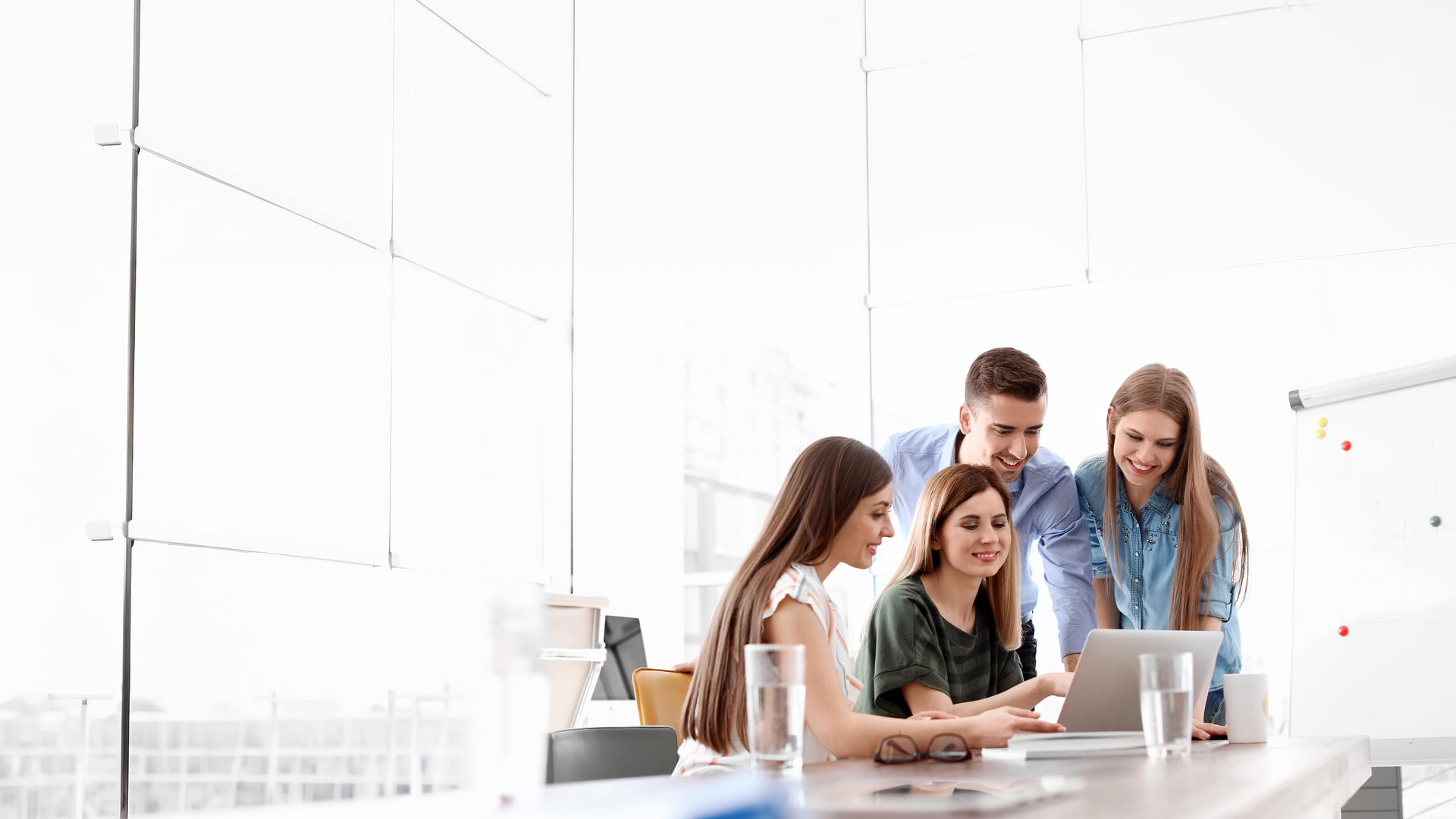 Young coworkers collaborating around laptop in office