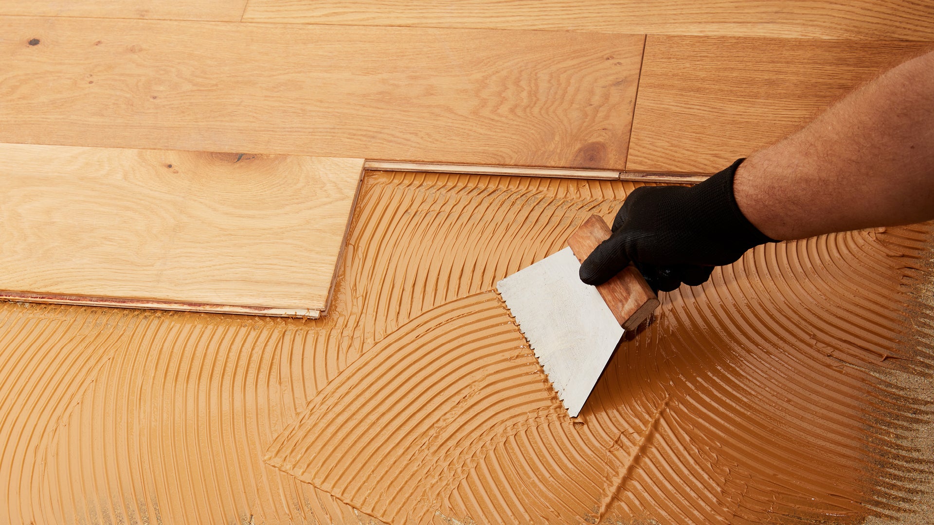 Person applying flooring adhesive to floor