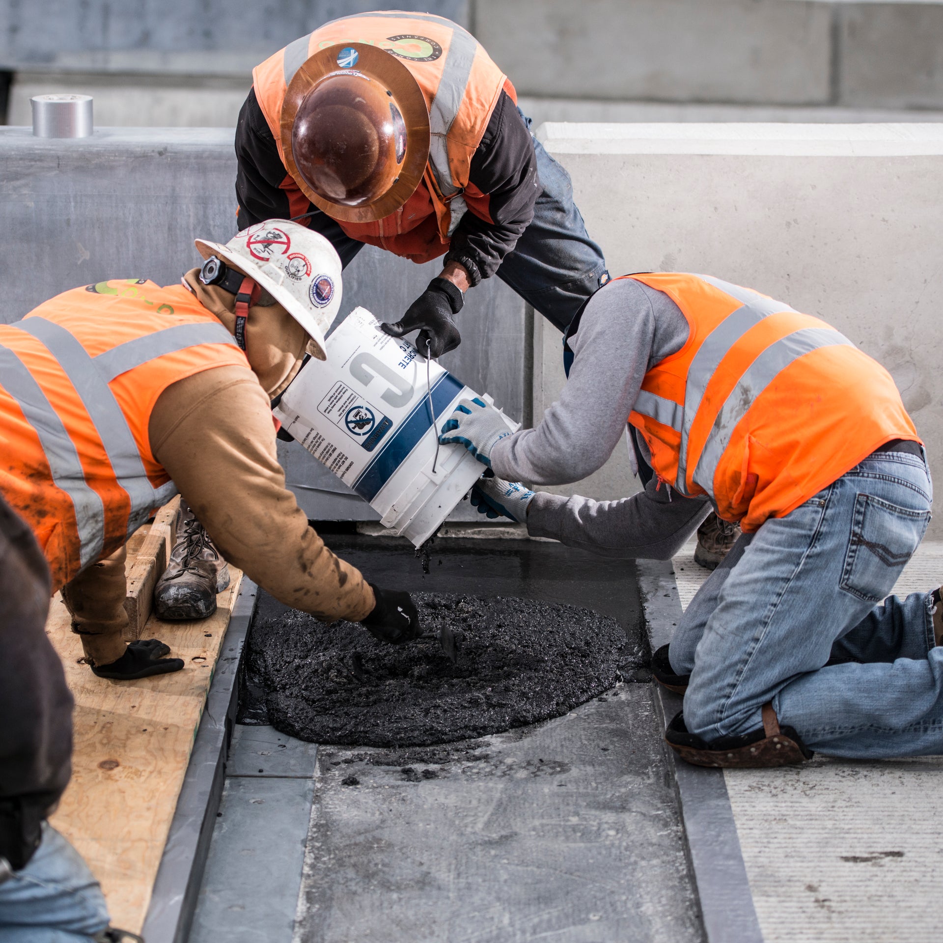 Construction workers pouring material into trench